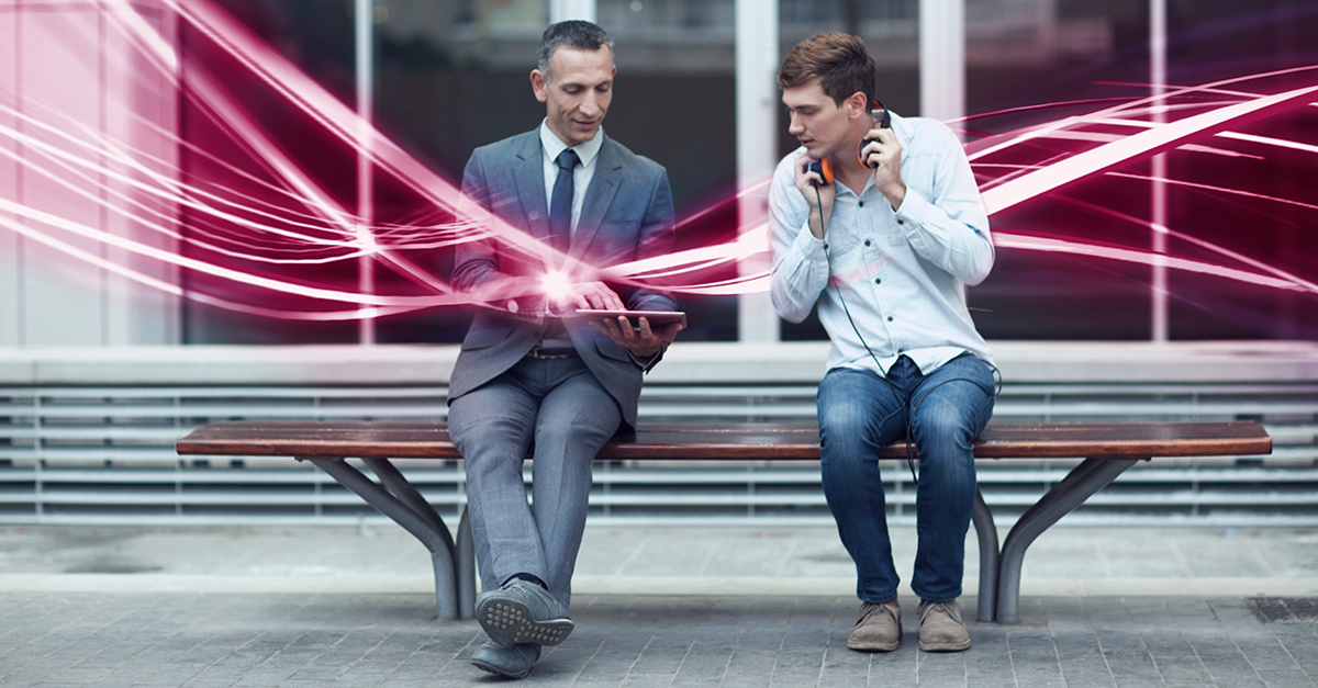 Foto von zwei Männern auf einer Bank, die auf ein Tablet schauen - durch das Bild laufen pink-weiße Lichtlinien